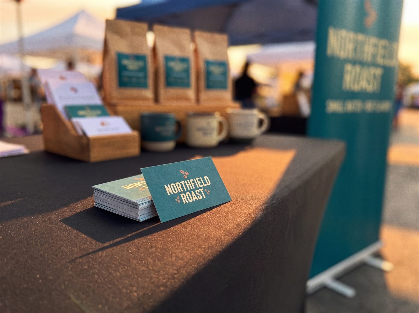A stack of business cards on the black stretch table cover, one card standing face-up, the booth blurred behind